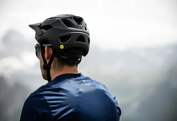 Rückansicht eines Mannes, der einen schwarzen Mountainbike-Helm mit Mips-Aufkleber trägt.