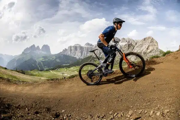 Ein Mountainbiker fährt auf einem staubigen Trail mit Blick auf Berge im Hintergrund.