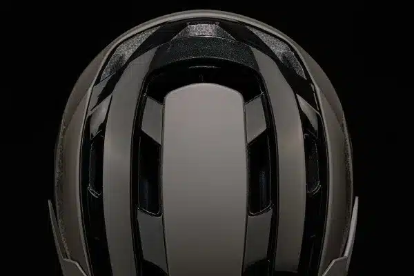 Detailaufnahme der Oberseite und Rückseite eines dunklen Mountainbike-Helms mit Belüftungsöffnungen und glänzenden schwarzen Akzenten.