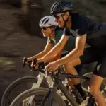 Zwei Radfahrer fahren nebeneinander mit ihren S-Works Turbo Creo 2 E-Gravelbikes auf einem Schotterweg.