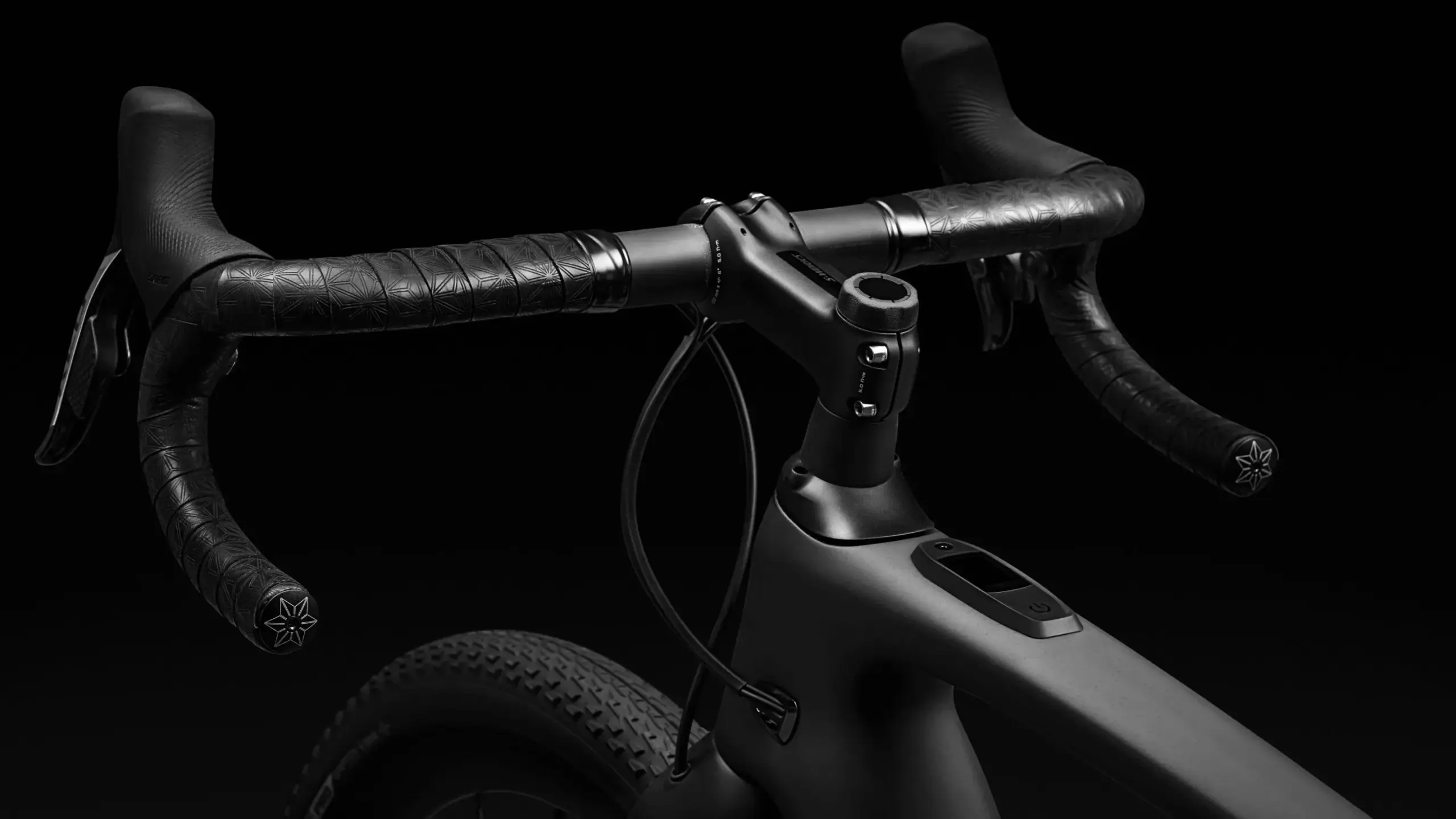 Dunkle Nahaufnahme des Lenkers mit integrierter Elektronik und des vorderen Rahmens eines S-Works Turbo Creo 2 E-Bikes.