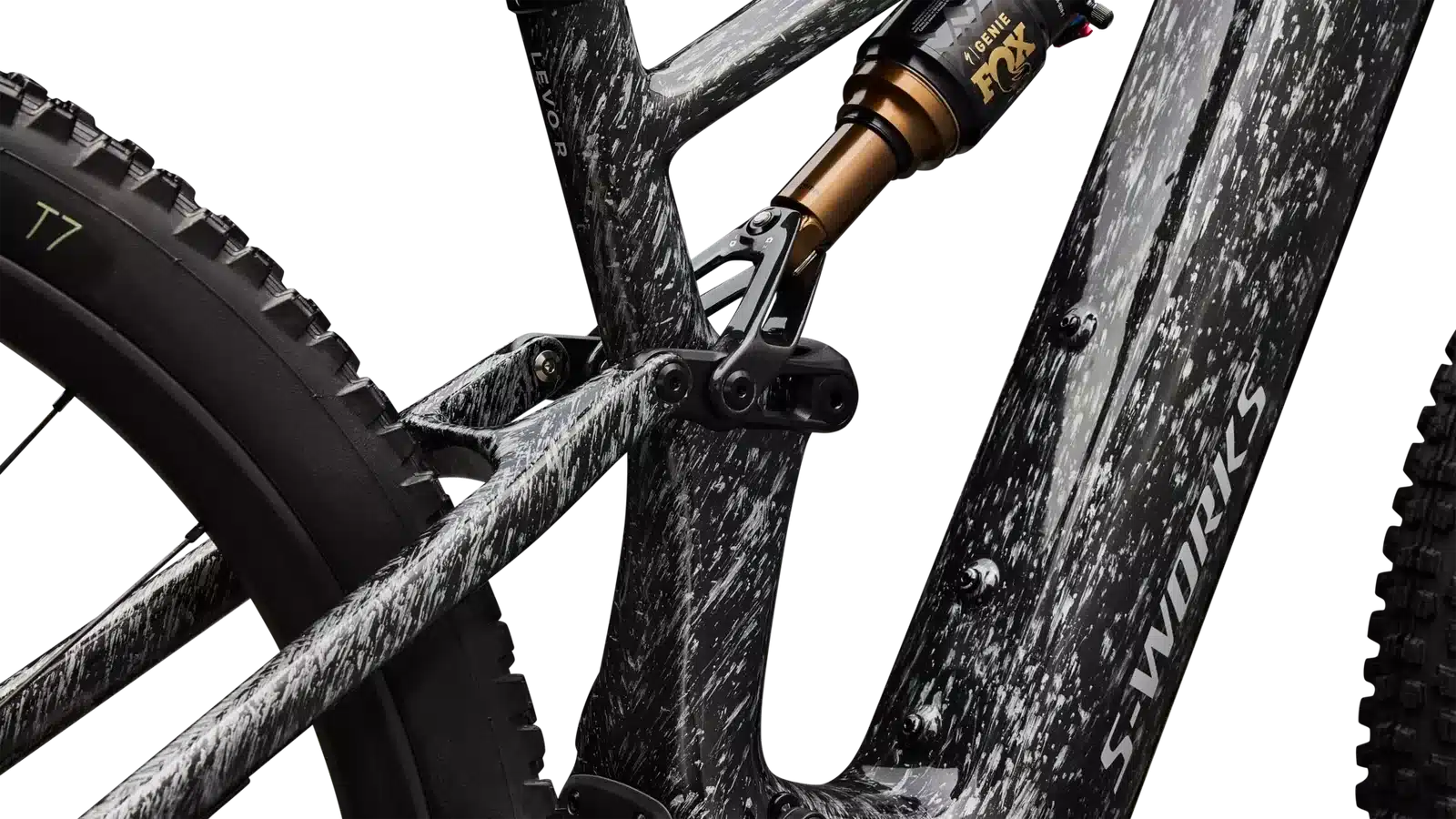 Detailaufnahme des Hinterbaus eines S-Works Turbo Levo R E-Mountainbikes, Fokus auf den Dämpfer, die Umlenkung und das auffällige Tarnmuster des Carbonrahmens.