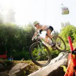 Mountainbiker auf einem SCOTT Spark RC World Cup, der eine felsige Abfahrt hinunterfährt. Eine Gondelbahn ist im Hintergrund zu sehen.