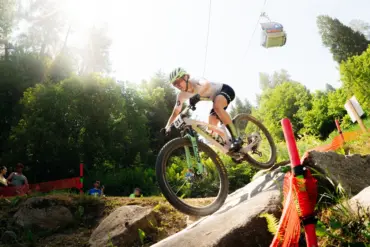 Mountainbiker auf einem SCOTT Spark RC World Cup, der eine felsige Abfahrt hinunterfährt. Eine Gondelbahn ist im Hintergrund zu sehen.