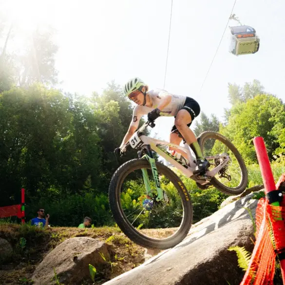 Mountainbiker auf einem SCOTT Spark RC World Cup, der eine felsige Abfahrt hinunterfährt. Eine Gondelbahn ist im Hintergrund zu sehen.