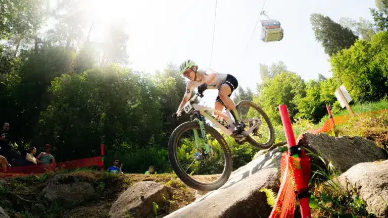 Mountainbiker auf einem SCOTT Spark RC World Cup, der eine felsige Abfahrt hinunterfährt. Eine Gondelbahn ist im Hintergrund zu sehen.