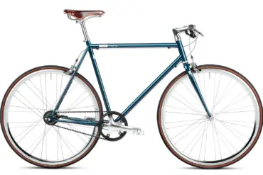 Seitenansicht eines petrolfarbenen Urban Bikes mit braunem Brooks-Ledersattel, Riemenantrieb und weißen Felgen.