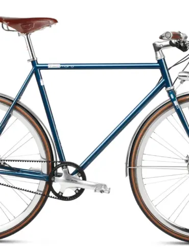 Seitenansicht des Solid Petrol Urban Deluxe Bikes, einem dunkelblauen Fahrrad mit braunem Ledersattel, Riemenantrieb und integrierter Lichtanlage.