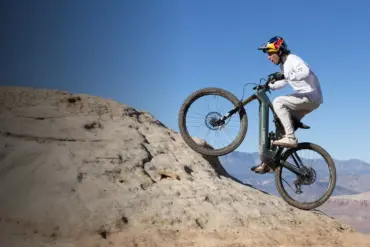 Mountainbiker fährt das Specialized Turbo Levo R Expert auf einem felsigen Hang mit blauem Himmel.