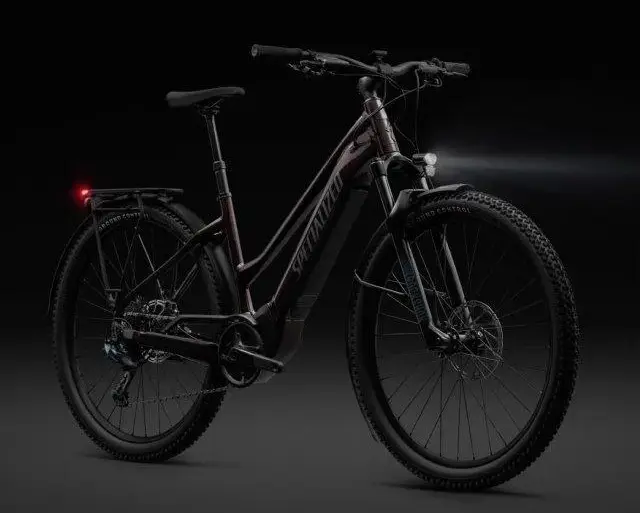 Dunkelrotes Specialized Turbo Tero 5.0 EQ E-Bike mit schwarzem Gepäckträger, Schutzblechen, Vorder- und Rücklicht auf dunklem Hintergrund.