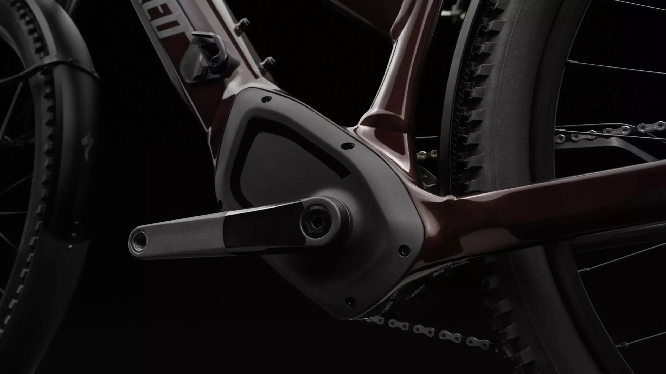 Detailaufnahme des Antriebsstrangs eines dunkelroten Specialized Turbo Tero 5.0 EQ E-Bikes mit Fokus auf den Motor, die Kurbel und die Kette.
