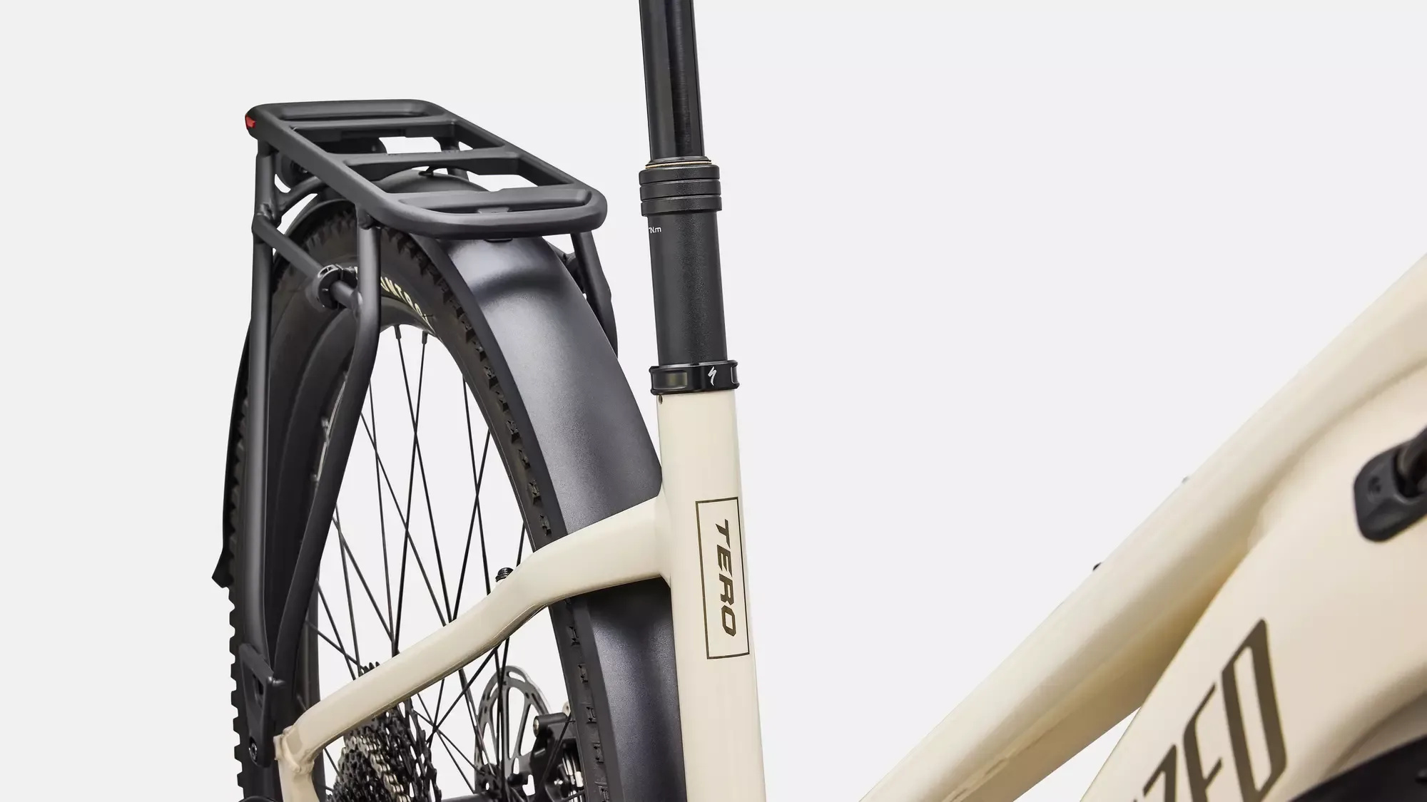 Detailaufnahme des Hinterrads, des Gepäckträgers und des Schutzblechs eines cremefarbenen Specialized Turbo Tero 5.0 EQ Step-Through E-Bikes.