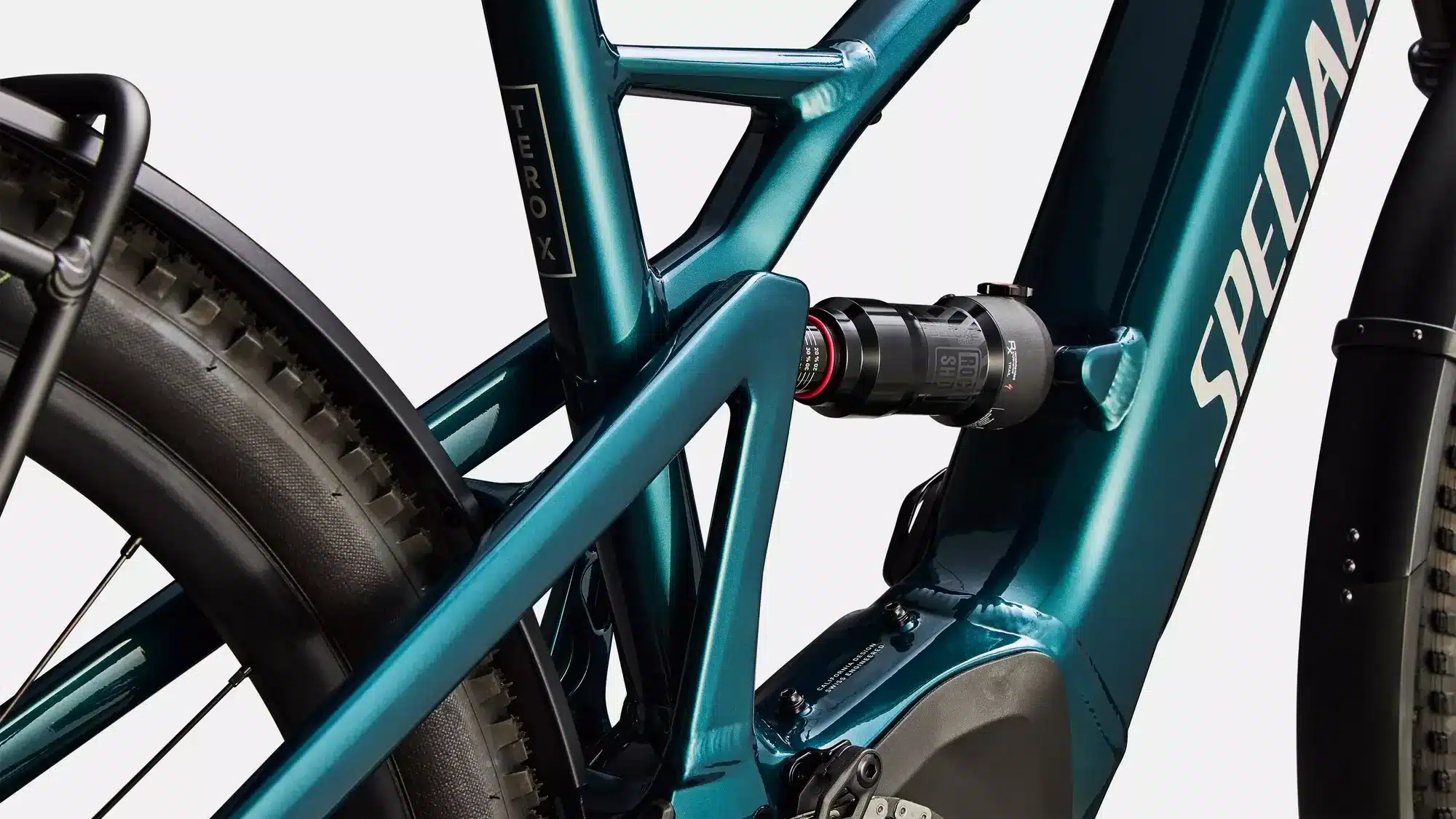 Detailansicht des tealfarbenen Rahmens des Specialized Turbo Tero X 5.0 E-Bikes mit Fokus auf den RockShox-Dämpfer und die Hinterradaufhängung.
