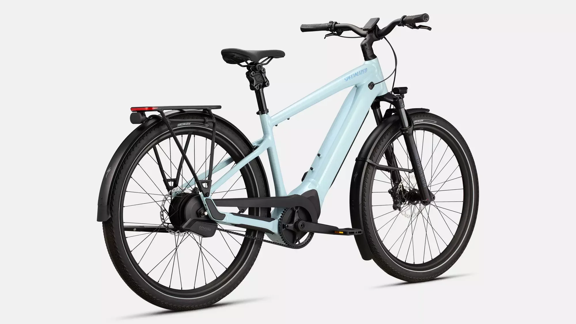 Sicht von hinten links auf ein Specialized Turbo Vado 5.0 IGH E-Bike in Hellblau, mit Fokus auf den Gepäckträger, das Hinterrad und den Riemenantrieb.