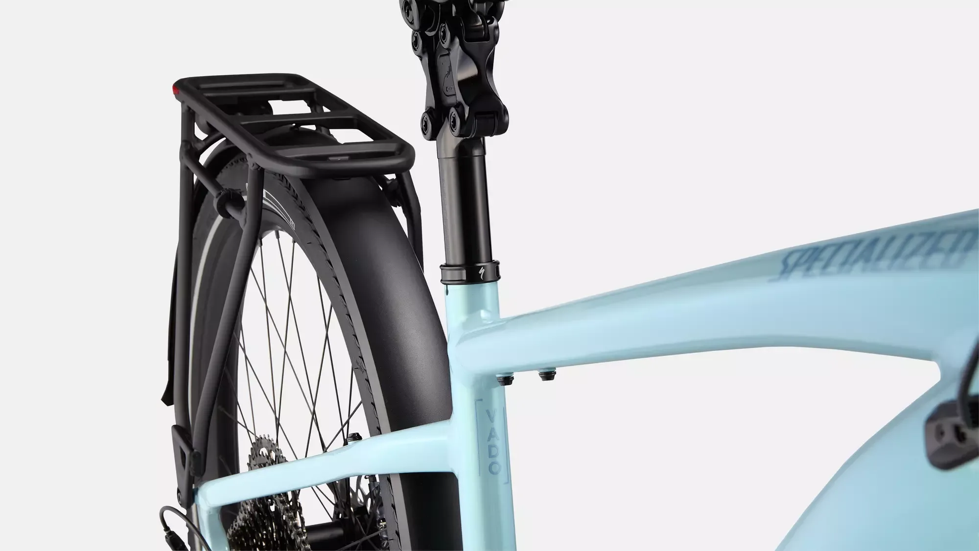 Detailansicht des hellblauen Specialized Turbo Vado 5.0 E-Bikes, gezeigt wird das Hinterrad mit Schutzblech, Gepäckträger und ein Teil des Rahmens mit dem Schriftzug