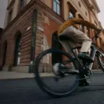 Mann fährt mit einem Specialized Turbo Vado SL 2 4.0 EQ E-Bike durch eine belebte Stadtstraße, mit Fokus auf das Fahrrad und seine Fahrdynamik.