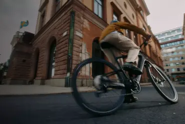 Mann fährt mit einem Specialized Turbo Vado SL 2 4.0 EQ E-Bike durch eine belebte Stadtstraße, mit Fokus auf das Fahrrad und seine Fahrdynamik.