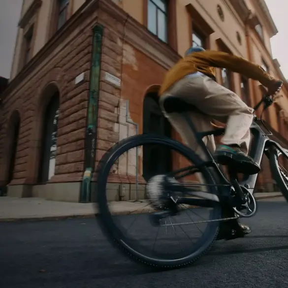 Mann fährt mit einem Specialized Turbo Vado SL 2 4.0 EQ E-Bike durch eine belebte Stadtstraße, mit Fokus auf das Fahrrad und seine Fahrdynamik.