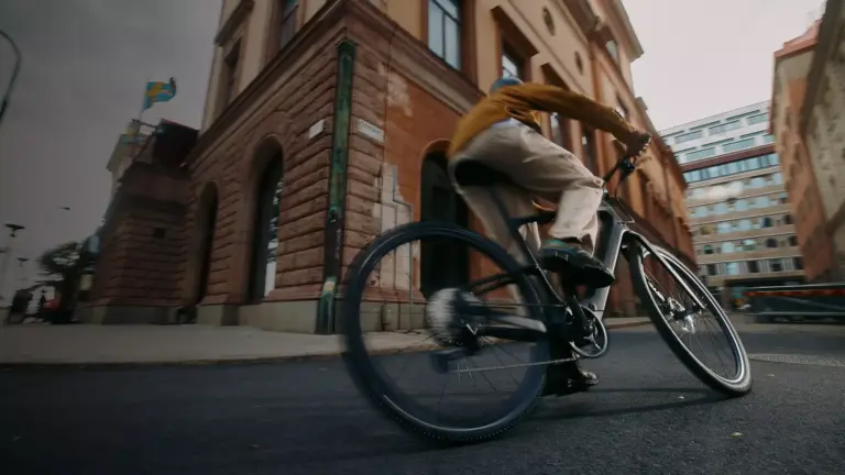 Mann fährt mit einem Specialized Turbo Vado SL 2 4.0 EQ E-Bike durch eine belebte Stadtstraße, mit Fokus auf das Fahrrad und seine Fahrdynamik.