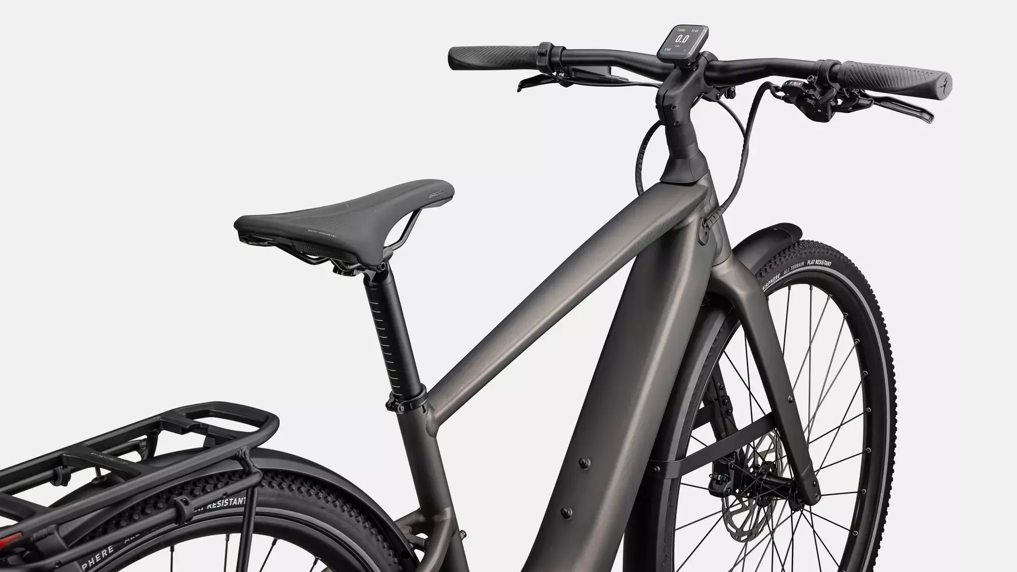 Nahaufnahme eines grauen Specialized Turbo Vado SL 2 4.0 EQ E-Bikes, Fokus auf den Rahmen, den Sattel, den Gepäckträger und das Cockpit mit Display.