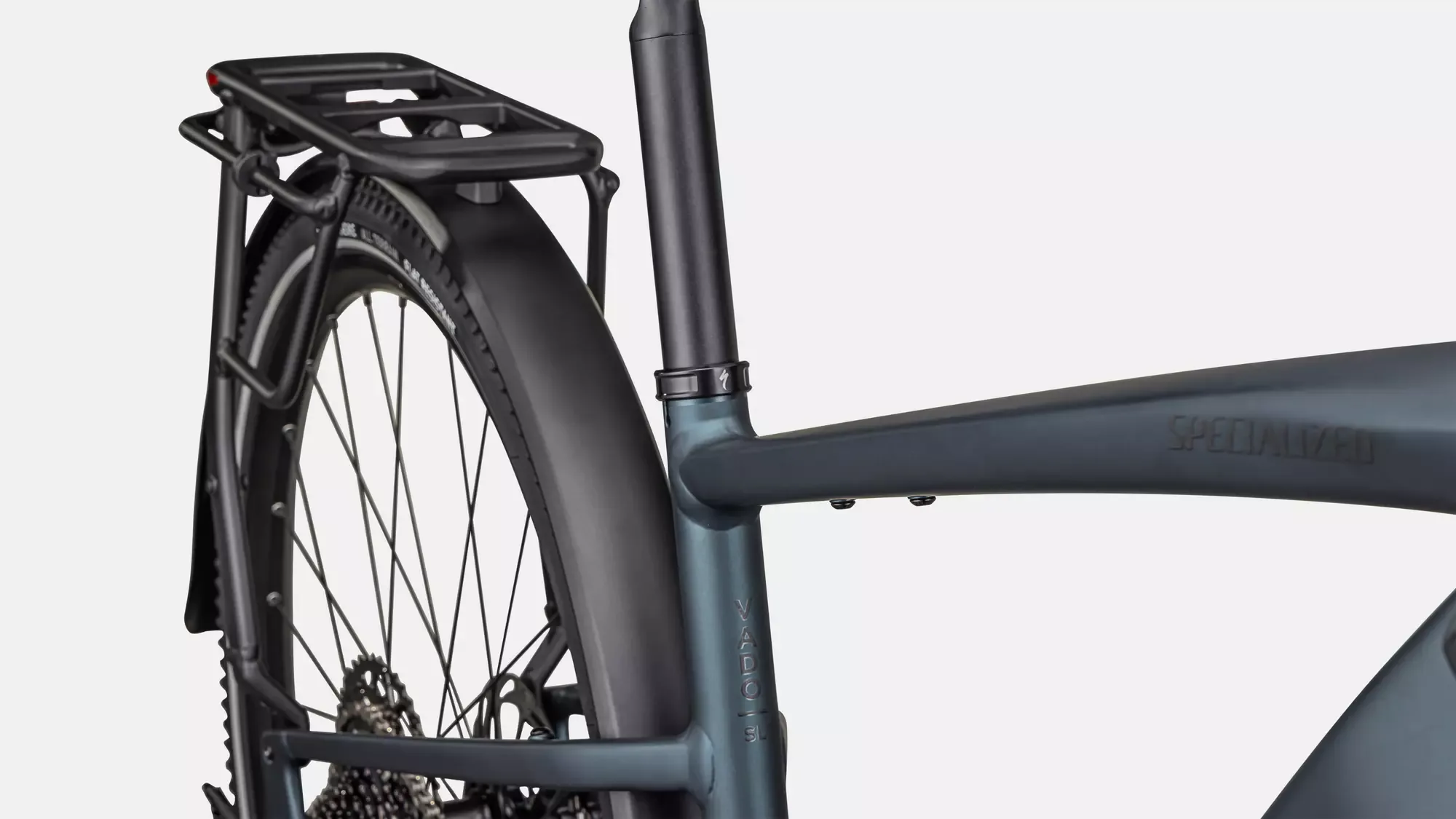 Detailaufnahme des Specialized Turbo Vado SL 2 5.0 EQ E-Bikes, das den hinteren Teil des Rahmens mit integriertem Gepäckträger und Schutzblech zeigt. Der Schriftzug SPECIALIZED ist dezent in den Rahmen eingeprägt.