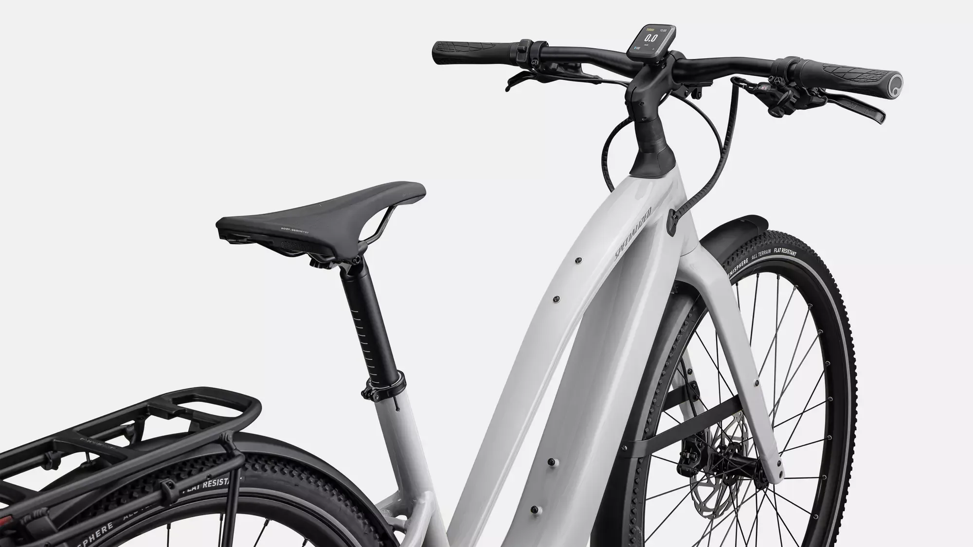 Detailansicht des Specialized Turbo Vado SL 2 5.0 Step-Through EQ E-Bikes, das einen Teil des Rahmens, den Sattel, den Gepäckträger und das Vorderrad zeigt.