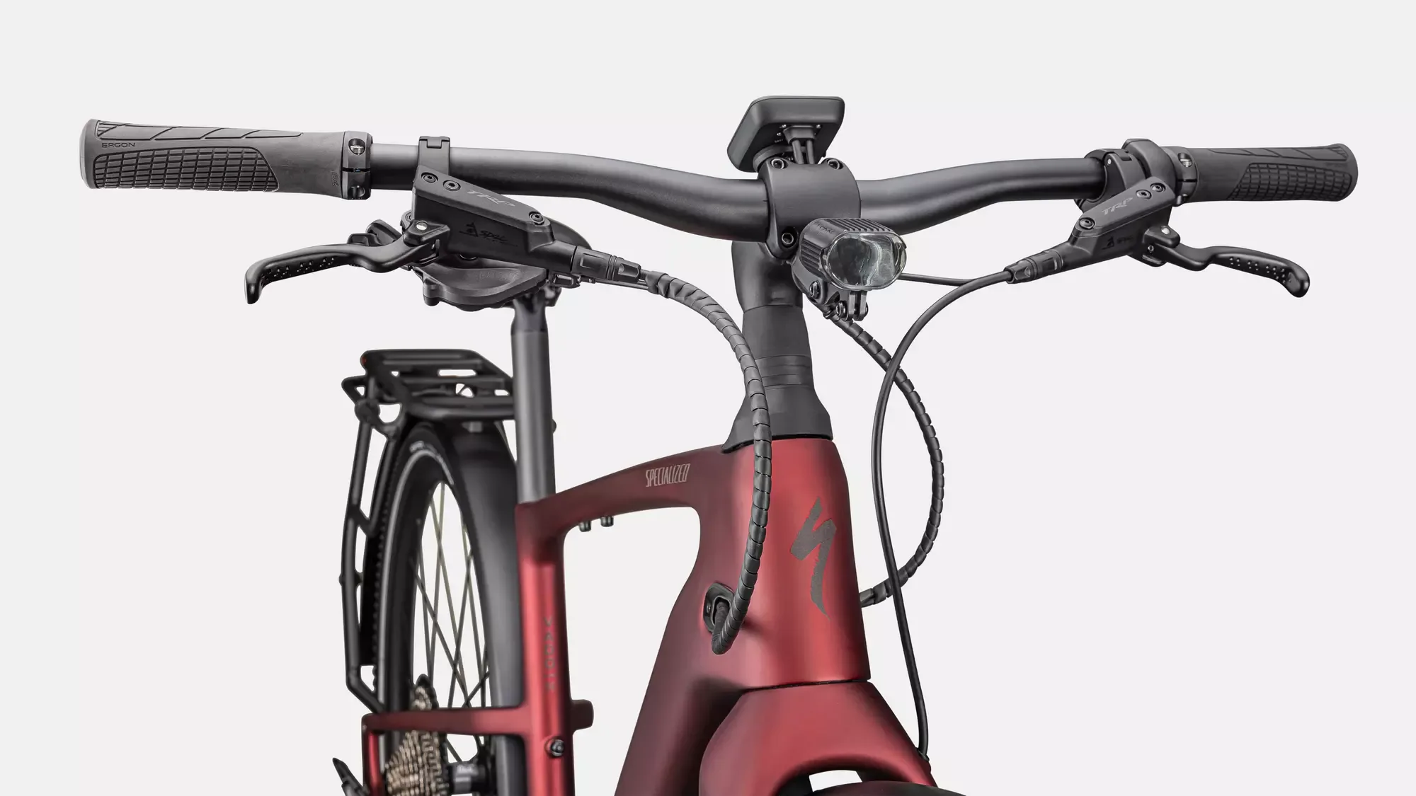 Detailansicht des roten Carbonrahmens, des Lenkers mit Griffen, Bremsen, Display und Frontlicht eines Specialized Turbo Vado SL 2 6.0 EQ Carbon E-Bikes.