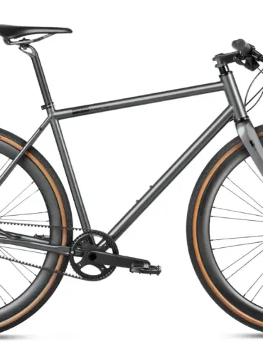 Seitenansicht eines stark grey Gravelbikes mit Stahlrahmen, Flatbar-Lenker, Gates Carbon Drive Riemenantrieb und Continental Terra Speed Reifen.