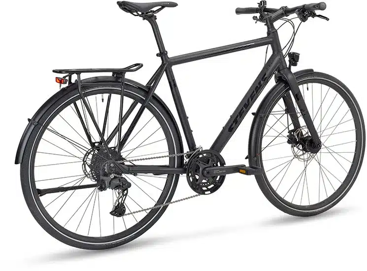 Seitenansicht eines schwarzen Stevens 6X Lite Tour HT Fahrrads mit Gepäckträger, Schutzblechen, Nabendynamo und Kettenschaltung.