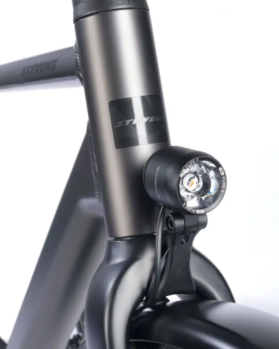 Detailaufnahme des schwarzen Supernova E3 Pure 3 LED-Scheinwerfers, montiert an der Gabelkrone eines dunklen Stevens Caleta 9.1 HT Trekkingrads.