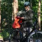 Ein Mann bereitet sein Stevens Caleta 9.2 LT Trekkingrad für eine Tour vor, indem er eine Tasche auf den Gepäckträger lädt.
