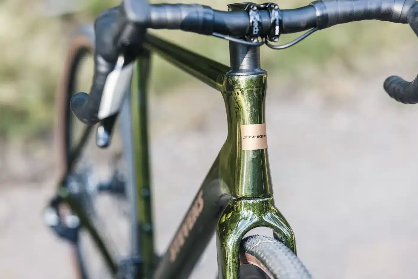 Nahaufnahme des grünen Stevens Camino RS Gravelbikes, die das Steuersatzrohr, den Lenker und die Gabel zeigt.