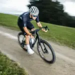 Ein Rennradfahrer fährt mit einem schwarzen Stevens Camino RS Pro AXS Gravelbike auf einem Schotterweg in hügeliger Landschaft.