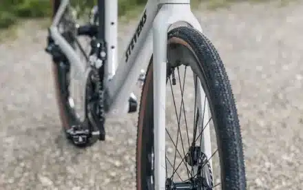 Nahaufnahme des Vorderrads eines weißen Stevens Camino RS Pro Di2 Gravelbikes mit schwarzem Reifenprofil und Speichen.