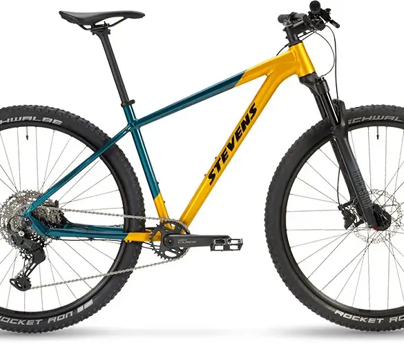 Seitenansicht eines Stevens Devil's Trail Mountainbikes in Gelb-Türkis mit schwarzen Reifen und Federgabel.