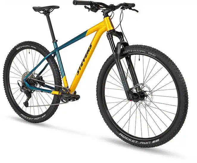 Stevens Devil's Trail Mountainbike in Petrol Gold und Dunkelgrün mit gelbem Rahmen, schwarzen Reifen und Federgabel.