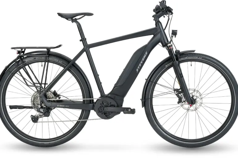 Seitenansicht eines schwarzen Stevens E-6X Tour HT E-Tourenrads mit voll integriertem Bosch-Akku, Gepäckträger und Federgabel.