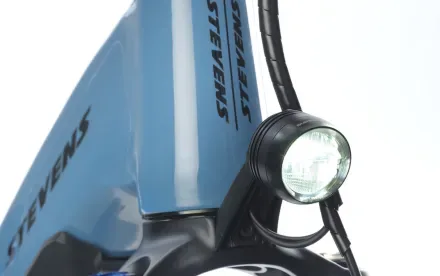 Nahaufnahme des Frontscheinwerfers eines STEVENS E-8X Tour Plus HT E-Bikes, der hell aufleuchtet.