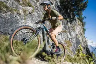 Frau fährt Stevens E-Agnello 7.8.1 E-Mountainbike bergauf auf felsigem Trail.