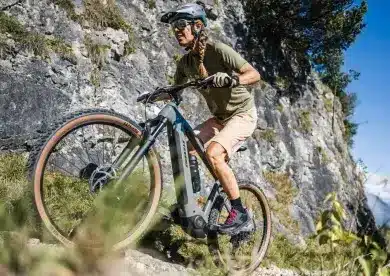 Frau fährt Stevens E-Agnello 7.8.1 E-Mountainbike bergauf auf felsigem Trail.