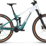 Seitenansicht des Stevens E-Maverick AM 7.4.3, einem weißen und türkisfarbenen E-Mountainbike mit Carbonrahmen und braunen Reifen.