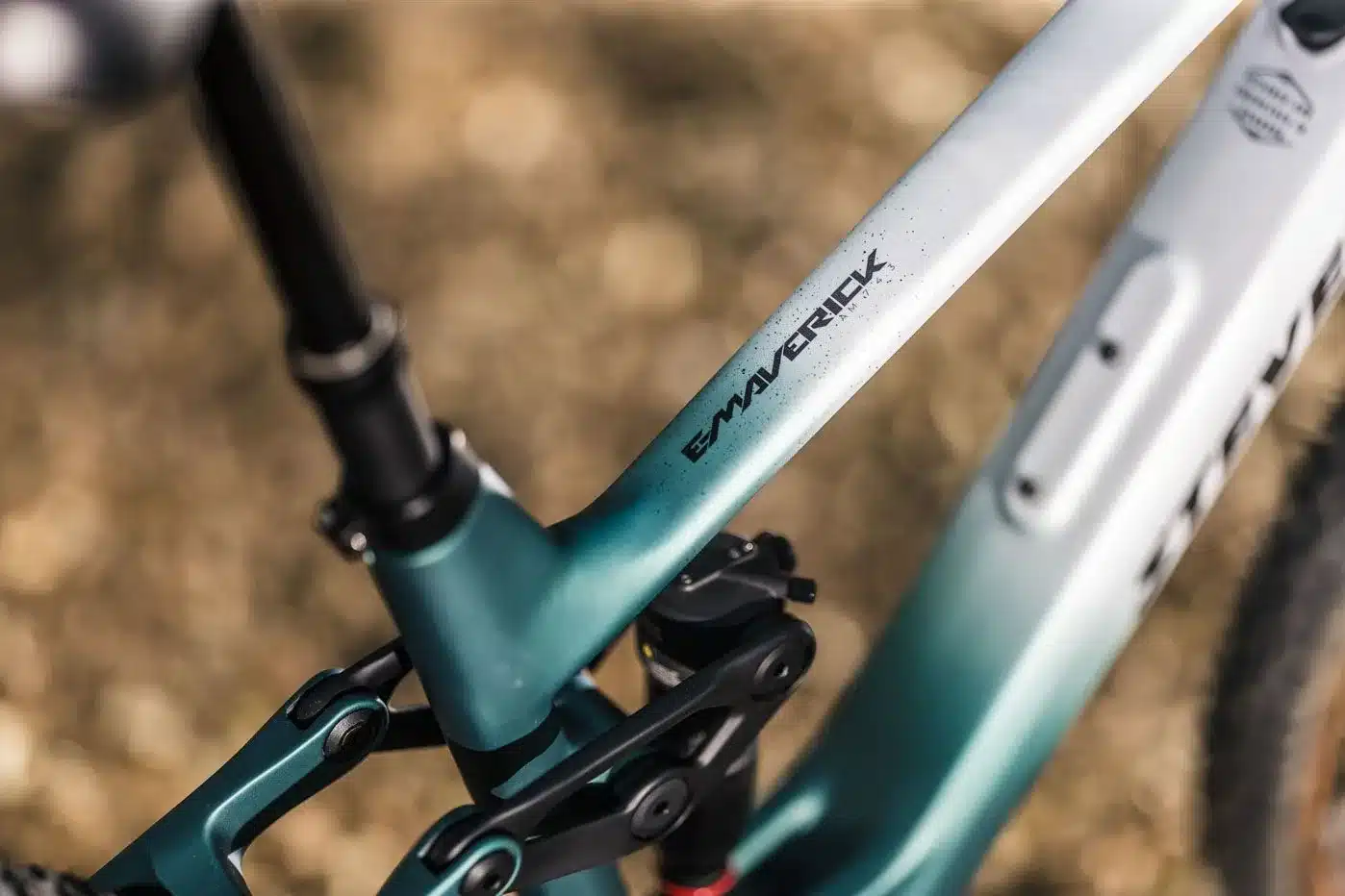 Nahaufnahme des Rahmens eines E-Mountainbikes der Marke Stevens, Modell E-Maverick AM 7.4.3, in Farbverlauf von Petrol zu Weiß.
