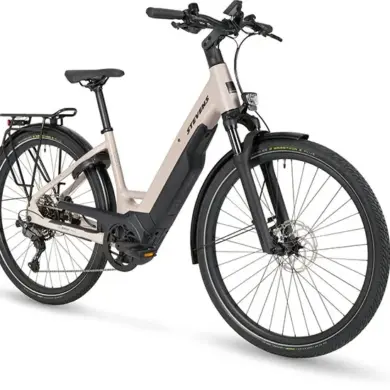 Seitenansicht eines beigefarbenen STEVENS E-Triton 7.8.1 Plus Forma Damen-E-Bikes mit tiefem Einstieg, Gepäckträger und Federgabel.