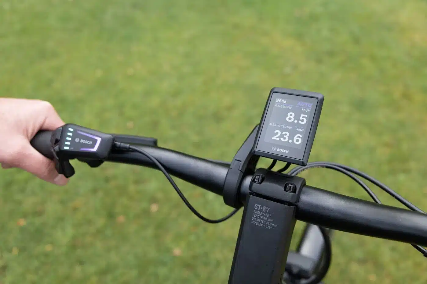 Nahaufnahme des Lenkers eines E-Bikes mit Bosch Display, das Geschwindigkeit und Batteriestand anzeigt, und der Bedieneinheit mit Beleuchtung.