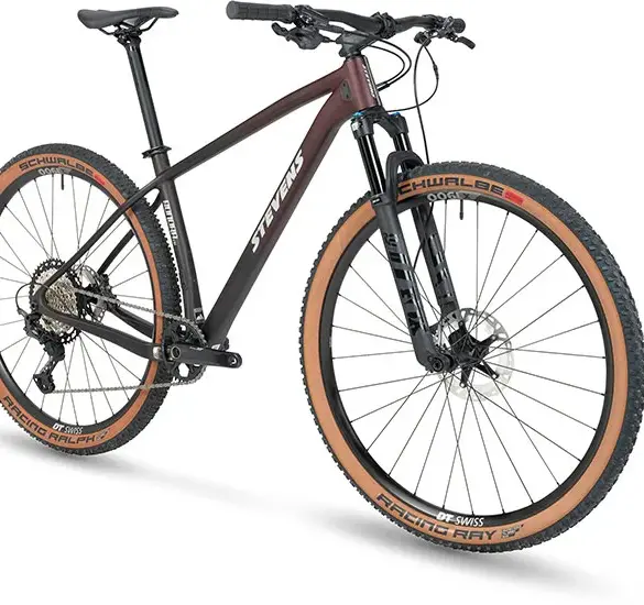 Stevens Sonora ES Mountainbike in sportlicher Seitenansicht, zeigt die Gabel und das Vorderrad mit braunen Reifen sowie den Carbonrahmen.