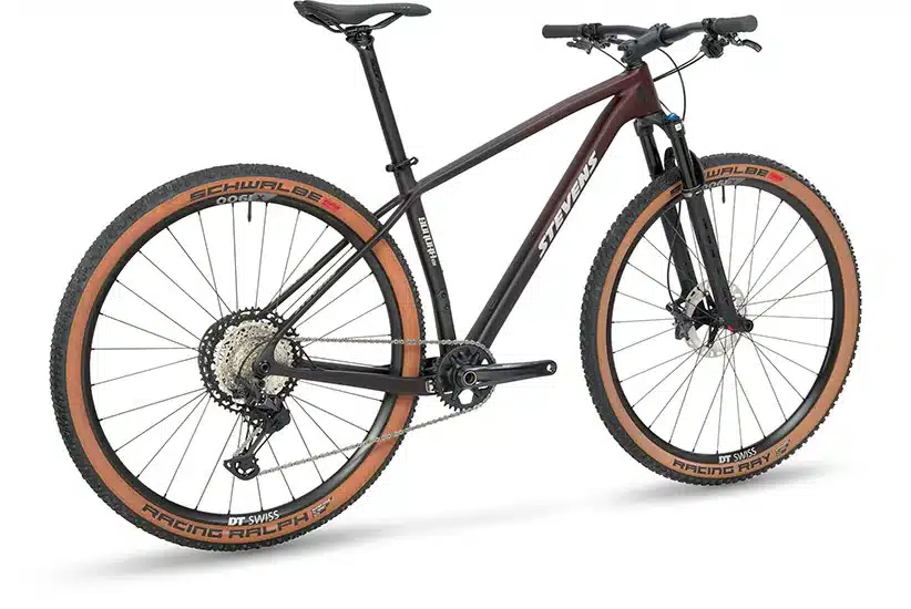 Seitenansicht des Stevens Sonora ES Mountainbikes, das sich durch seinen dunkelroten und schwarzen Carbonrahmen, die Fox 32 Federgabel, Shimano XT Komponenten und DT Swiss Laufräder auszeichnet.