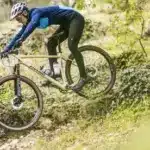 Mountainbikerin fährt das Stevens Sonora GX AXS auf einem steinigen Trail.