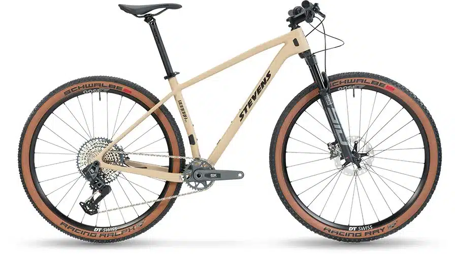 Seitenansicht eines sandfarbenen Stevens Sonora GX AXS Mountainbikes mit braunen Reifen und schwarzer Federgabel.