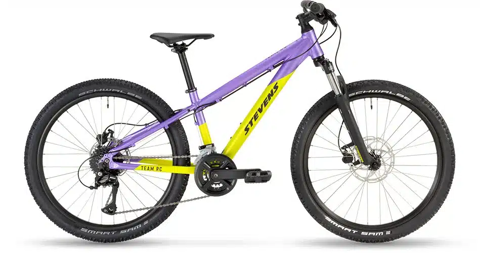 Seitenansicht eines lilac- und gelbfarbenen Stevens Team RC 24 Junior-Trail-Bikes mit 24-Zoll-Rädern und Federgabel.
