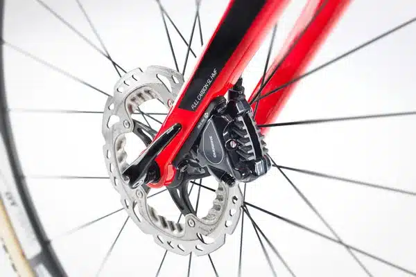 Nahaufnahme der Scheibenbremse eines roten STEVENS Vapor 2x12 Cyclocrossers mit schwarzen Speichen.